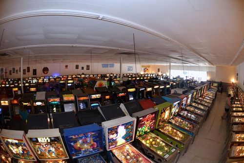 A wide view of a large arcade filled with numerous pinball machines and arcade cabinets.