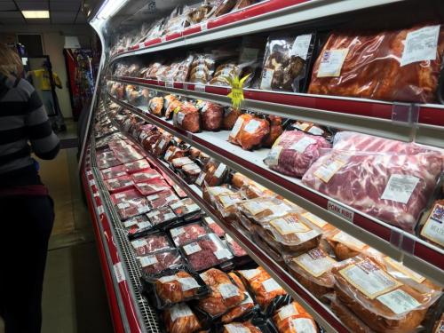 A refrigerated display case filled with various packaged meats in a grocery store.