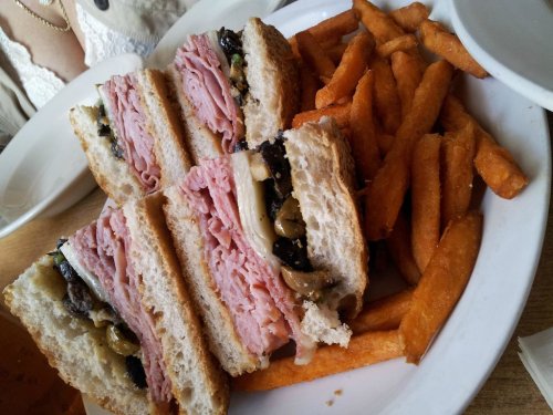 A stacked sandwich with layers of ham, mushrooms, and cheese, served with a side of crispy sweet potato fries.