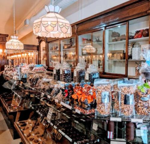A charming candy shop display filled with jars of sweets, chocolates, and treats under vintage light fixtures.