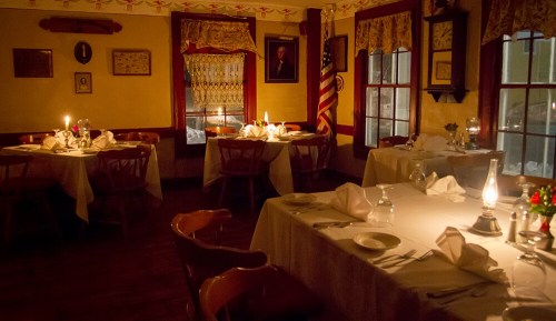 Cozy restaurant interior with candlelit tables, warm lighting, and rustic decor, creating an inviting atmosphere.