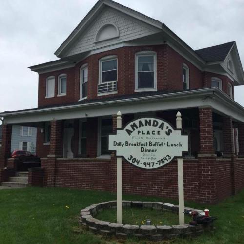 A brick building with a sign for "Amanda's Place" offering breakfast, lunch, and dinner. Green lawn in front.
