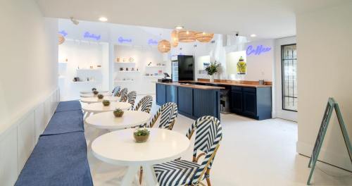 Bright café interior with white walls, blue accents, round tables, and stylish chairs, featuring a coffee bar and decor.