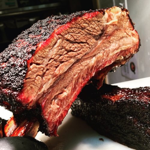 Close-up of a perfectly smoked beef brisket with a dark, crispy crust and tender, juicy interior.