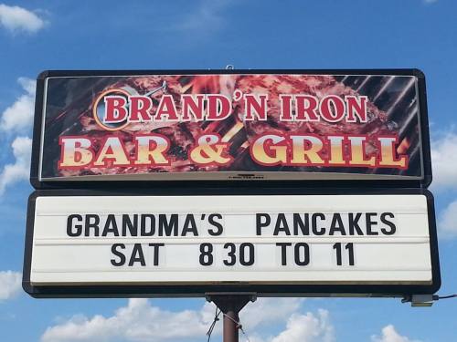 Sign for Brand'n Iron Bar & Grill advertising "Grandma's Pancakes" on Saturdays from 8:30 to 11 AM.