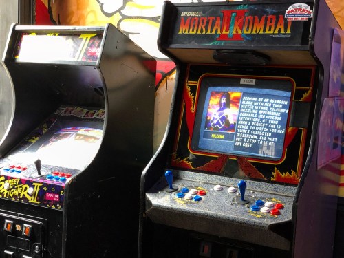 Two vintage arcade machines: "Mortal Kombat II" on the right and "Street Fighter II" on the left, set against a colorful backdrop.