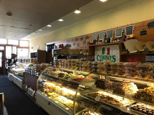 A bakery display filled with various pastries and desserts, featuring a sign that reads "Corbo's" in an inviting interior.