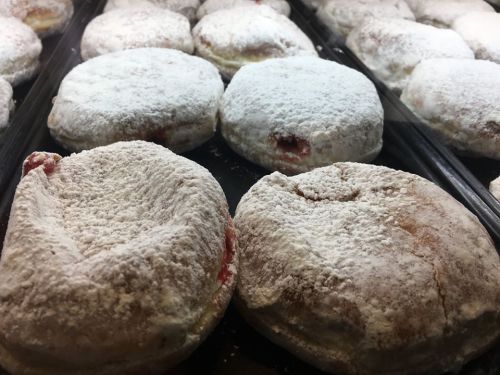 A close-up of powdered sugar-dusted pastries with a hint of red filling, arranged in a tray.