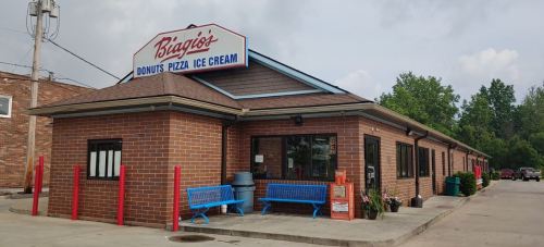 A brick building with a sign reading "Biggio's Donut's Pizza Ice Cream," featuring blue benches outside.