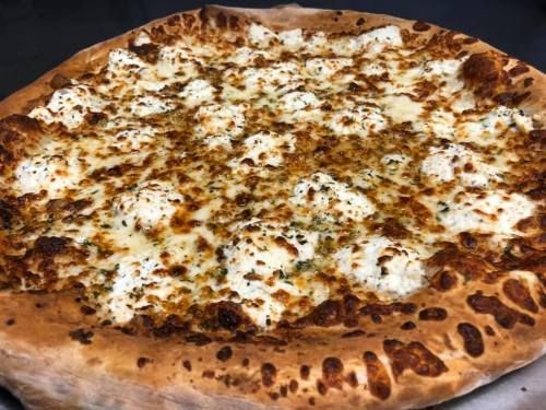 A close-up of a cheesy pizza with golden-brown crust and dollops of ricotta cheese on top.