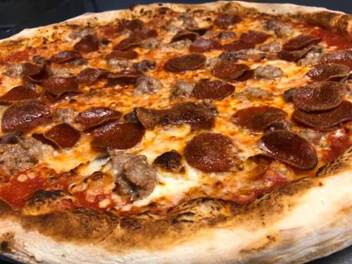 A close-up of a freshly baked pizza topped with pepperoni and sausage on a golden crust.