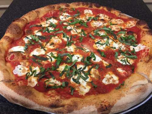 A freshly baked pizza topped with tomato sauce, mozzarella cheese, and fresh basil on a golden crust.