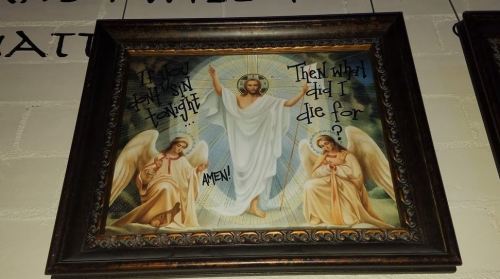 A framed religious artwork depicting Jesus with angels, featuring text questioning the purpose of his sacrifice.