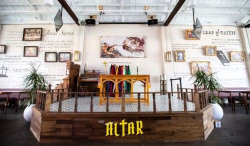A modern altar space with wooden decor, plants, and inspirational wall art in a bright, open setting.