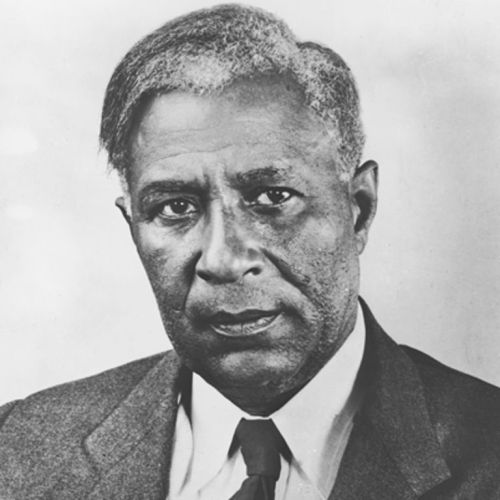 Black and white portrait of a serious man in a suit, with short, graying hair and a focused expression.
