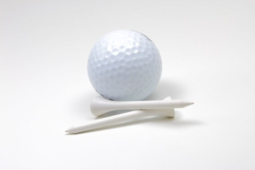 A white golf ball with two white tees on a plain background.