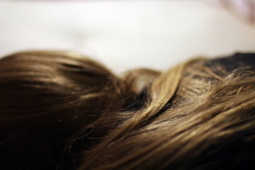 Close-up of long, wavy brown hair resting on a surface, with soft lighting creating a warm atmosphere.