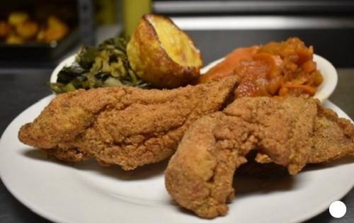A plate of crispy fried fish fillets with collard greens, sweet potatoes, and cornbread.