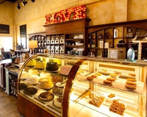 A cozy bakery display with various cakes and cookies, featuring a "LOVE" sign in the background.