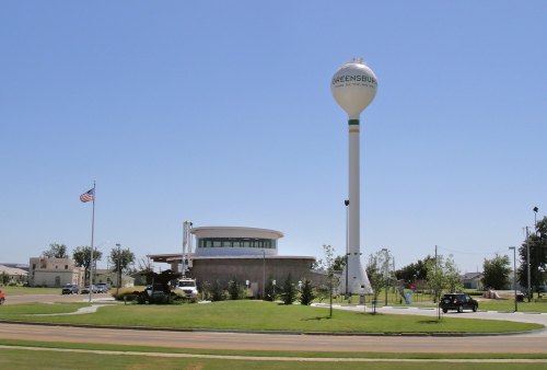Water tower and modern building in Greensburg, Kansas, with clear blue sky and green landscaping.