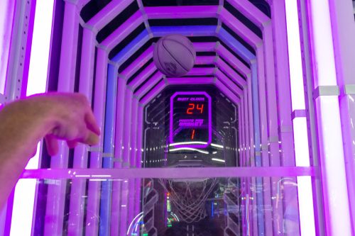 A basketball is shot towards a glowing arcade hoop, with a digital score display showing 24 points.