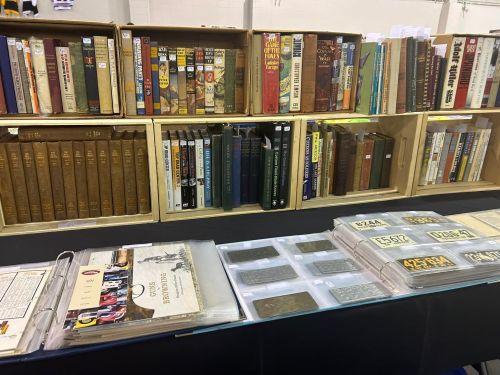 A display of various books and documents on shelves and tables at a book fair or market.