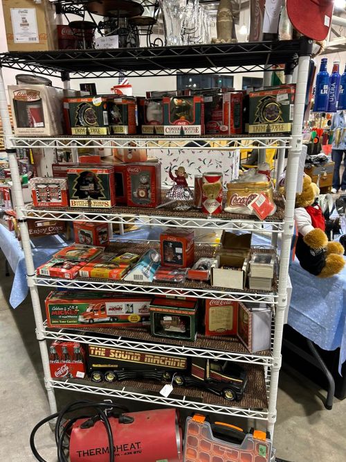 A display shelf filled with various vintage items, including toys, collectibles, and Coca-Cola memorabilia.