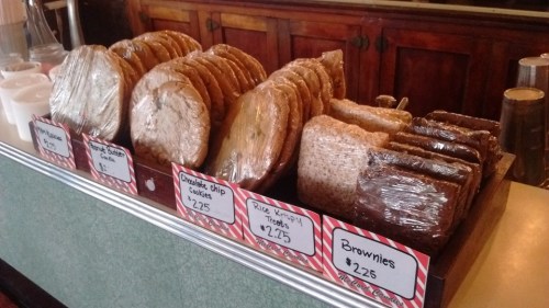 A display of assorted baked goods, including cookies and brownies, with prices labeled on festive tags.