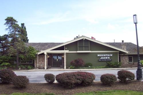 Exterior view of Mountain Jack's restaurant, featuring a stone and wood facade, surrounded by neatly trimmed bushes.