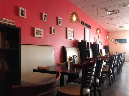 Interior of a restaurant with red walls, white booths, wooden tables, and framed photos on the wall. Sunflowers on tables.