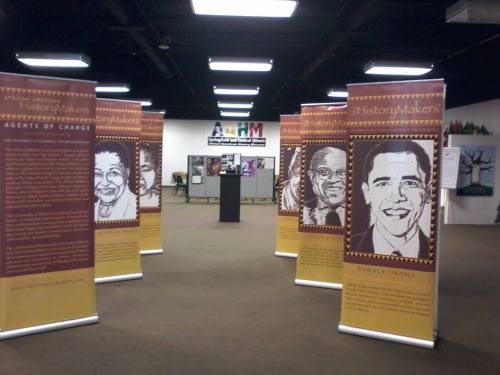 Exhibit featuring banners of notable African Americans, including Barack Obama, in a spacious gallery setting.