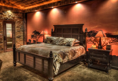 Cozy bedroom with a wooden bed, animal print bedding, and warm, earthy tones on the walls and decor.