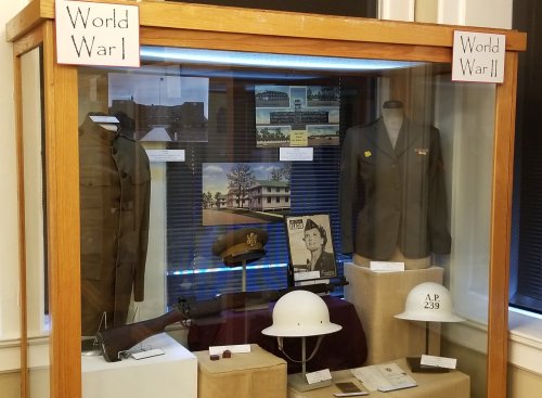 Display case featuring uniforms and artifacts from World War I and World War II, with informative labels.