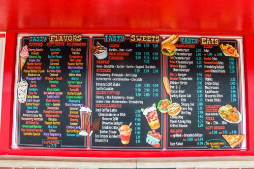Menu board featuring various ice cream flavors, sweets, and food items with prices listed. Brightly colored and eye-catching.