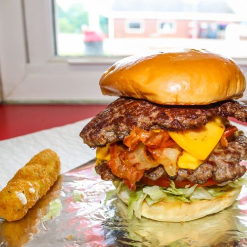 A towering burger with two patties, cheese, bacon, lettuce, and tomato, served with a side of crispy fried food.