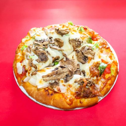 A freshly baked pizza topped with mushrooms, cheese, and vegetables on a red background.