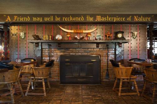 Cozy restaurant interior featuring a brick fireplace, wooden chairs, and a quote on the wall about friendship and nature.