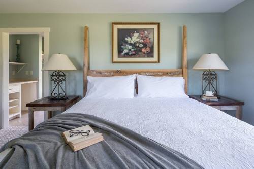 Cozy bedroom featuring a wooden bed, two lamps, a floral painting, and a book on the bedside table.