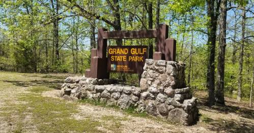 Sign for Grand Gulf State Park, surrounded by trees and grassy area, with a stone base.
