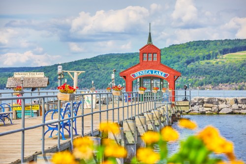 A colorful pier at Seneca Lake, featuring a red building and vibrant flowers in the foreground against a scenic backdrop.