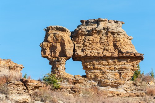 A unique rock formation resembling a face, set against a clear blue sky.
