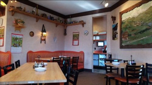 Cozy restaurant interior with wooden tables, chairs, and decorative wall art, featuring a warm, inviting atmosphere.
