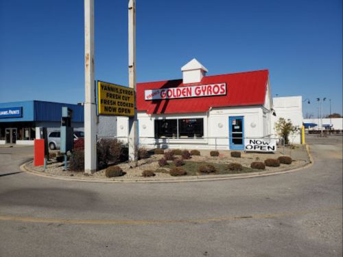 A restaurant called Golden Gyros with a red roof, featuring signs that say "Now Open" and "Fresh Cooked."