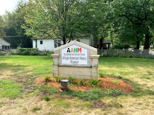 Sign for the African American History Museum in Springfield, Illinois, surrounded by greenery and a grassy area.