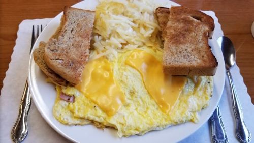 A plate of breakfast featuring an omelette with cheese, hash browns, and two slices of toasted bread.