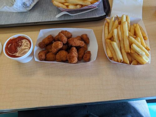 A tray with a serving of golden fries, crispy chicken nuggets, and a small cup of dipping sauce.