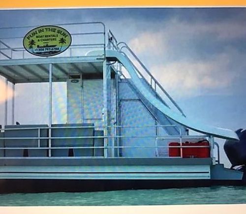A boat with a slide on the side, featuring a sign that reads "Fun in the Sun Boat Rentals & Charters."