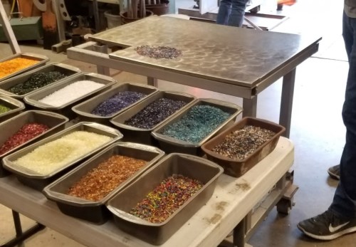 A table with various trays of colorful glass beads arranged neatly, ready for crafting or art projects.
