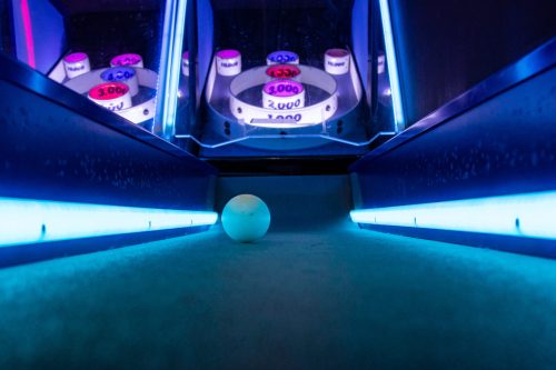 A close-up of a white ball on a glowing blue surface, with reflections in a mirrored background.