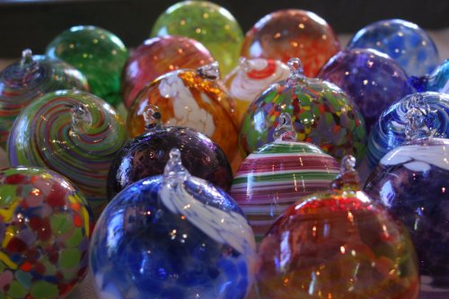 A colorful assortment of glass ornaments in various patterns and hues, arranged closely together.